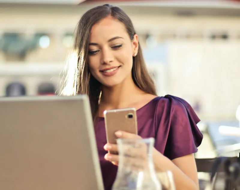 Smiling user with phone and laptop, representing customer perception and satisfaction.